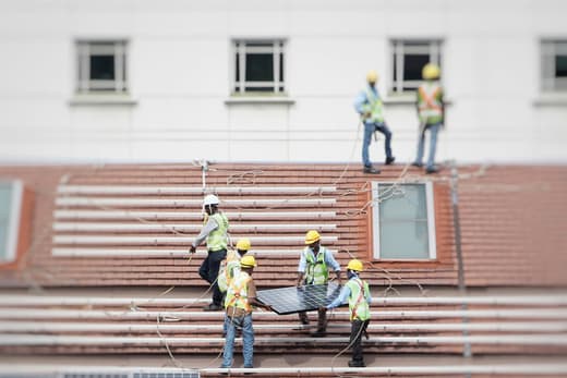 Équipe d’installateurs posant des panneaux solaires sur une toiture en tuiles