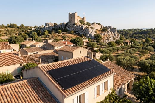 Toiture solaire avec la tour du château en ruine dominant le village d'Aureille — photo d'illustration