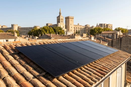 Panneaux solaires en toiture avec le Palais des Papes et les remparts d'Avignon en arrière-plan — photo d'illustration